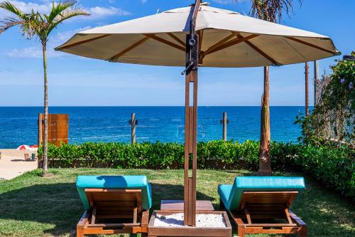 two chairs and an umbrella next to the ocean at Residencial Marina Del Sol in Pauba