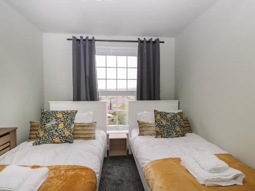 two beds in a room with a window at North Harbour House in Weymouth