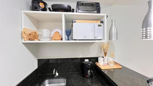 a kitchen counter with a sink and a microwave at Flat no Aldeia das Águas Park Resort in Barra do Piraí