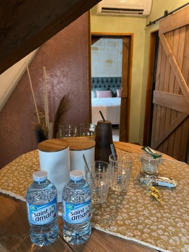a table with two bottles of water and glasses on it at Espace bien être Jacuzzi in Saint-Amand-les-Eaux