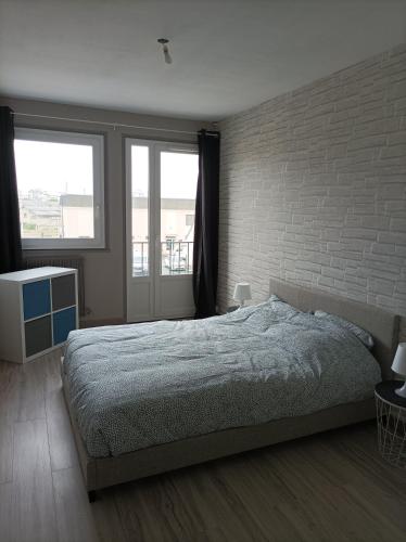 une chambre avec un lit et un mur de briques dans l'établissement Joli appartement type 5 en centre ville, à Châteauroux