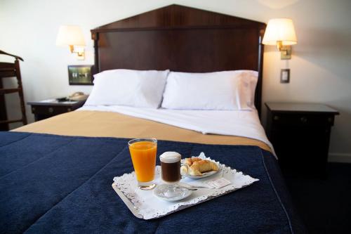 Una habitación de hotel con una bandeja de comida y bebidas en una cama. en Hotel Presidente Buenos Aires, en Buenos Aires