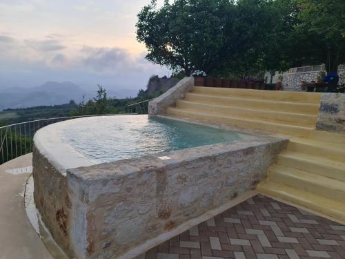 a stone fountain with stairs and a pool of water at ONOMY Country House Vathypetro in Archanes