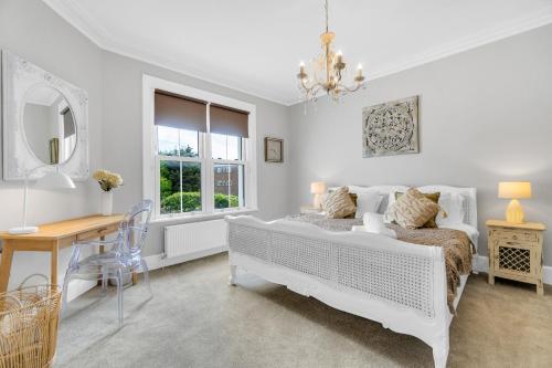 a white bedroom with a bed and a table and a desk at Poets Apartment with Free Parking By My Getaways in Worthing
