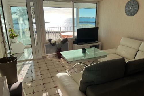 a living room with a couch and a glass table at Appartement Mar e Souleu avec Terrasse et Vue Mer au Grau du Roi in Le Grau-du-Roi