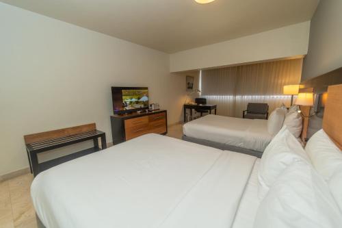 a hotel room with two beds and a television at Radisson Hotel Santo Domingo in Santo Domingo