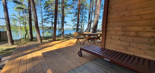 a wooden porch with a bench and a picnic table at Domki Borsk - nad samym jeziorem, nowe w pełni wyposażone z miejscem parkingowym in Borsk