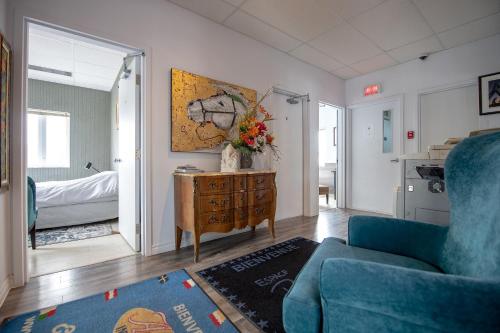 a living room with a blue couch and a bedroom at Auberge Internationale Espace Globetrotter in Rimouski