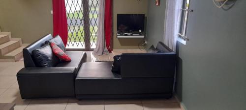 un divano nero in soggiorno con TV di La Maison de Vacances a Grande Gaube