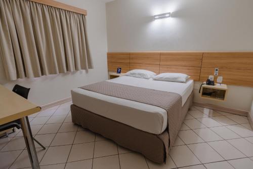 a bedroom with a bed and a table and a desk at Hotel Caiuá Express Umuarama in Umuarama