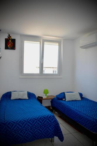 une chambre avec deux lits et deux fenêtres dans l'établissement L'annexe App'Art, à Sète