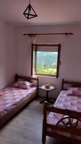 two beds in a room with a window and a table at Guest House Vodica in Virpazar