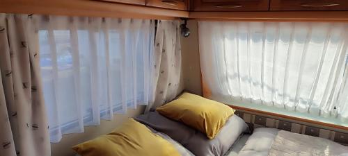 a small bed in a small room with a window at Przyczepa HOBBY - 2 minuty od Zatoki, przy wydmach, Kemping FlowCamp in Jastarnia