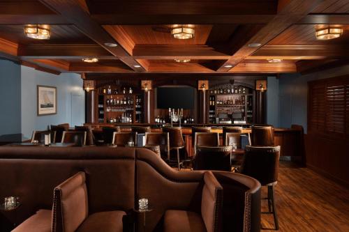 a bar with brown leather chairs and a television at The Karol Hotel, St. Petersburg Clearwater, a Tribute Portfolio Hotel in Clearwater