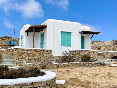 Casa blanca con puertas verdes y pared de piedra en Twins Apartments, en Fanari