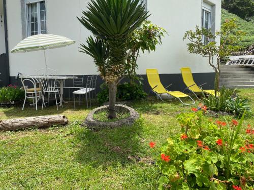 a table and chairs and a palm tree in a yard at Ocean Garden, 4 units by the ocean in São Vicente