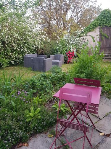 una mesa rosa y un banco en un jardín en Hameau de Leignoua, en Le Saint