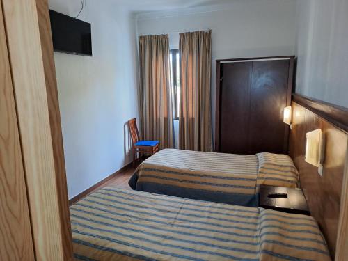 Una habitación de hotel con una cama con una manta a rayas. en Hotel Ribeira Grande, en Ribeira Grande
