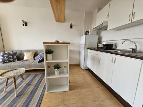 una cucina e un soggiorno con armadi bianchi e divano di Coqueto estudio cerca del mar ad Almerimar