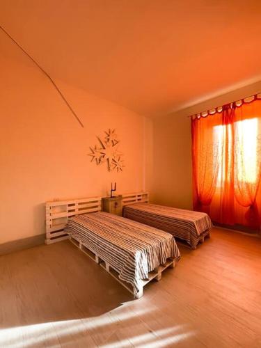 two beds in a room with an orange wall at Bau!House in Piombino