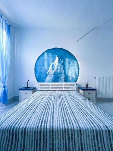 a blue bedroom with a bed with a painting of a wolf at Bau!House in Piombino