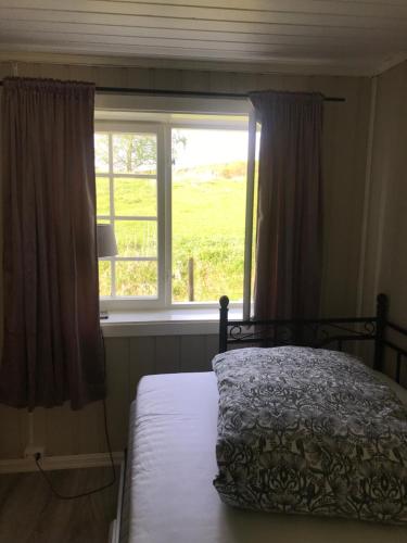 a bedroom with a bed in front of a window at Koselig hus på gård med 6 soverom in Gran