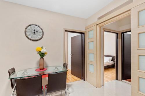a dining room with a glass table and a clock on the wall at Apartments Saxo in Kotor