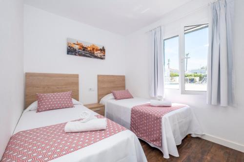 a room with two beds and a window at Apartamentos Llebeig in Ciutadella