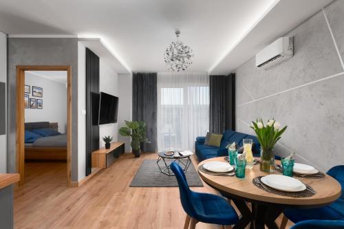 a living room with a table and blue chairs at Apartament Marina Loft & Spa Sagaris Dziwnów in Dziwnów