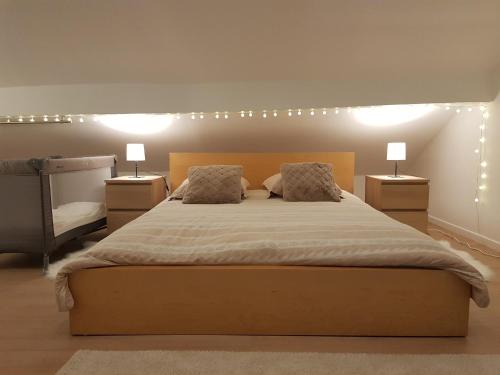 a bedroom with a large bed with two lamps on it at Charmante villa proche de la gare et de Paris in Les Pavillons-sous-Bois