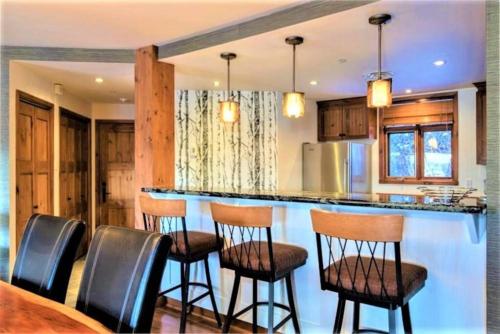 a kitchen with a bar with chairs around it at ALTITUDE 170-2 / PRIVATE Hot Tub on HUGE Terrace in Mont-Tremblant