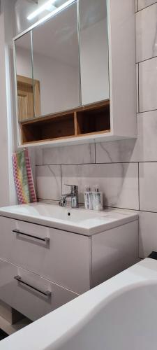 a white bathroom with a sink and a mirror at Cosy Apartment in City Center in Liepāja
