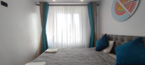 a bedroom with a bed with blue pillows and a window at Cosy Apartment in City Center in Liepāja