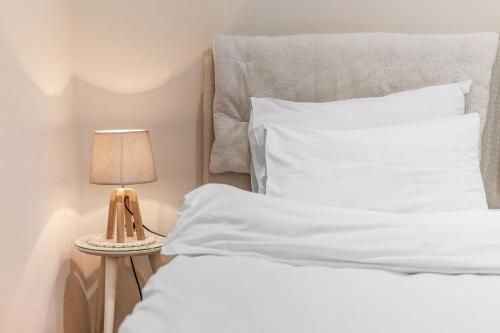 a bed with white sheets and a lamp on a table at Apartments Saxo in Kotor