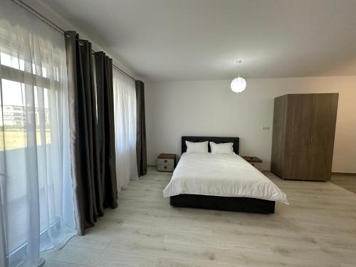 Parma Residence في Giroc: غرفة نوم بسرير ونافذة كبيرة