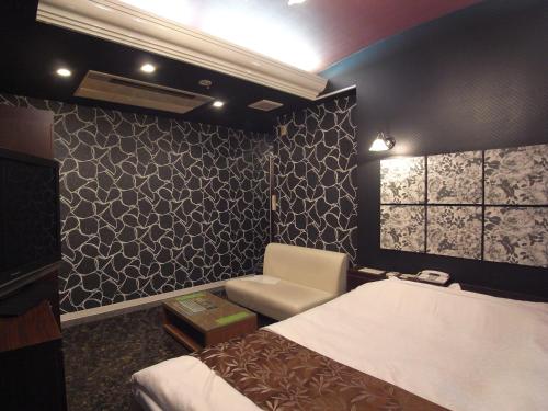 a bedroom with a bed and a chair and a window at ホテル カルネヴァール 男塾ホテルグループ in Himeji