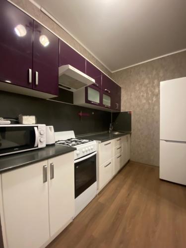 a kitchen with white appliances and purple cabinets at Комфортабельные - Уютные апартаменты в Костанай Алтын Арман in Kostanay