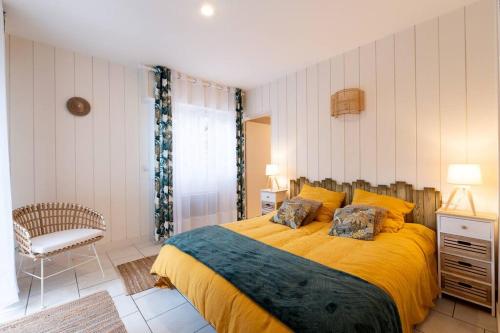 - une chambre avec un lit avec des draps jaunes et une chaise dans l'établissement Villa calme du golf avec piscine proche du lac, à Biscarrosse