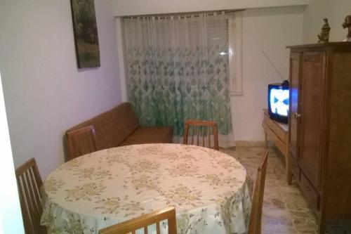 sala de estar con mesa, sofá y TV en Miramar departamento 2 ambientes frente al mar en Miramar