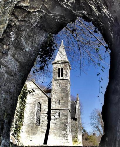 an old stone church with a tower and a steeple at Glandore mews situated in the picturesque village of Glandore in Glandore