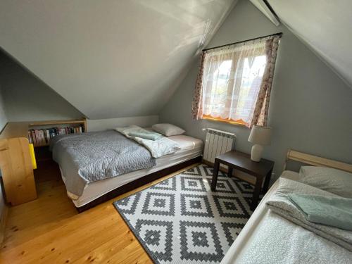 a attic bedroom with two beds and a window at Czym Chata Bogata in Korbielów