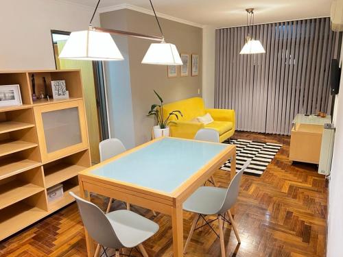 comedor con mesa y sillas y sofá amarillo en Larrañaga 2 dorm. Nueva Córdoba en Córdoba