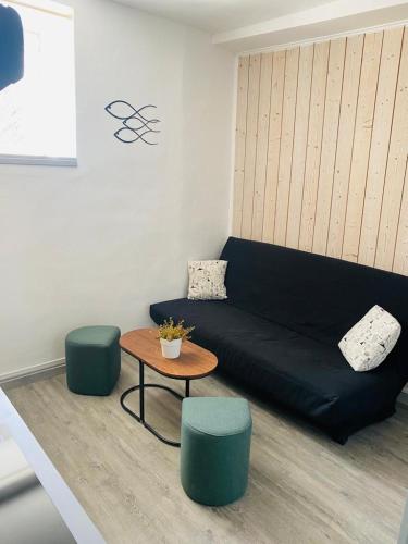 - un salon avec un canapé, deux tabourets et une table dans l'établissement studio coquet, au Guilvinec