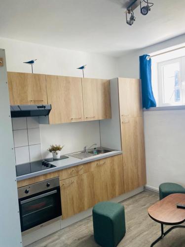 une cuisine avec des armoires en bois, un évier et une table dans l'établissement studio coquet, au Guilvinec