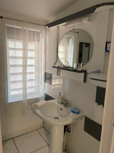 W białej łazience znajduje się umywalka i lustro. w obiekcie Kazajany w mieście Terre-de-Haut