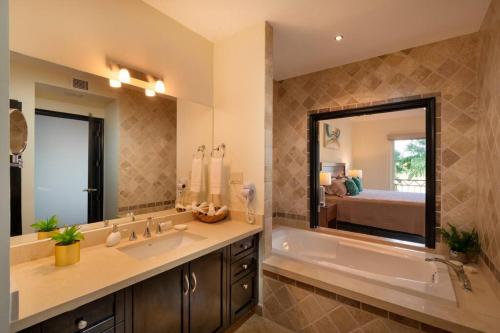 uma casa de banho com uma banheira e um espelho grande em Condo Maravilla - New luxurious condo 300mt from the beach em Cabo San Lucas