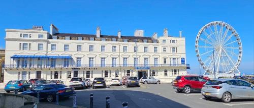 a large white building with a ferris wheel in a parking lot at NELSON Hotel in Great Yarmouth