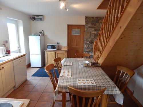 a kitchen with a table and chairs and a kitchen with a staircase at Burry Farm Cottage in Swansea