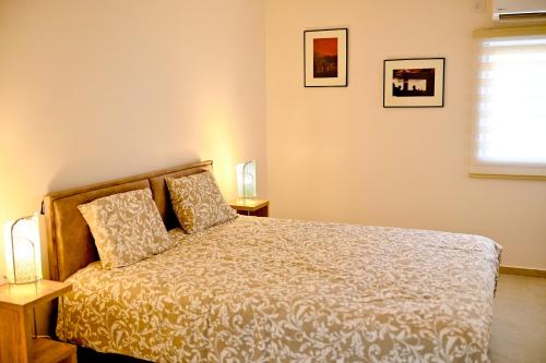 1 dormitorio con 1 cama, 2 lámparas y ventana en Topnatanya, en Netanya