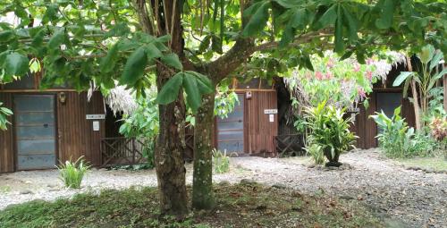 a building with two garage doors and a tree at Tortugal Boutique River Lodge in Rio Dulce